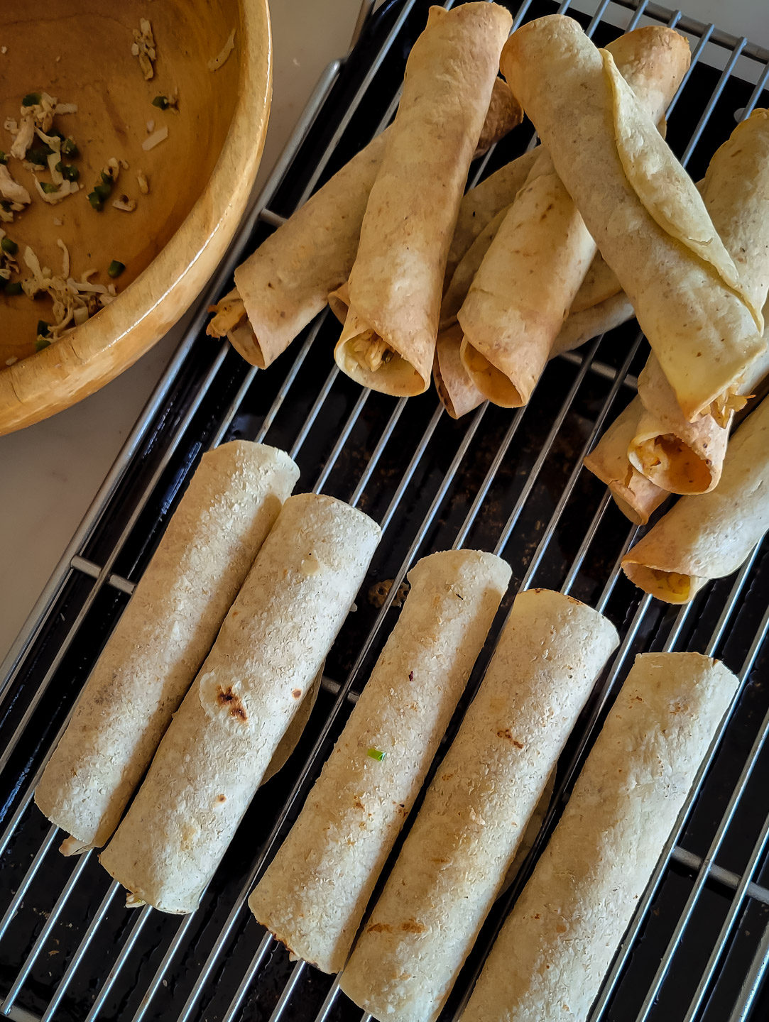 Rolled Chicken Taquitos on a wire rack set over a baking sheet