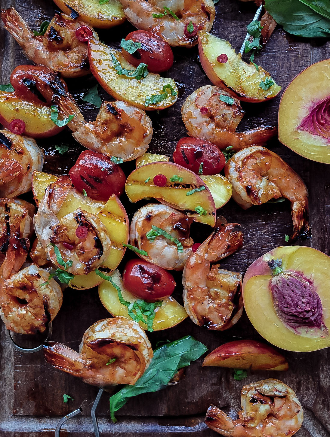 skewers of peach jam and sambel olek glazed shrimp, peaches and tomatoes, sprinkled with basil.