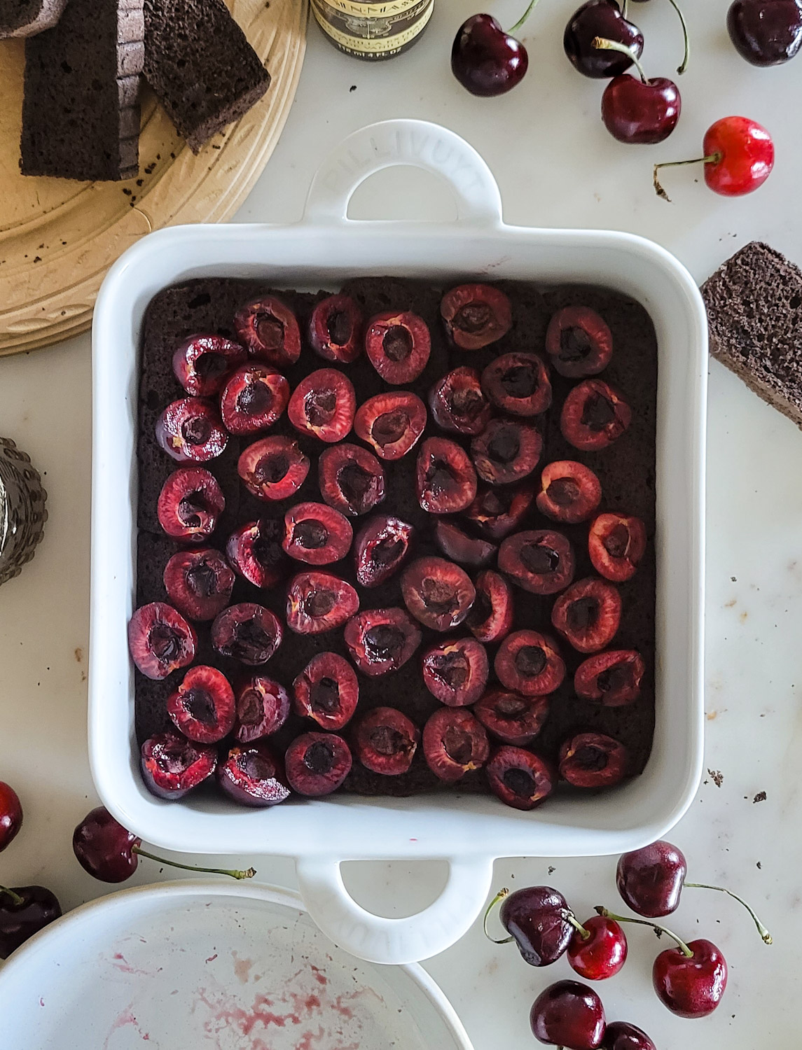 baking dish filled with chocolate sponge cake, layered with fresh cherries.