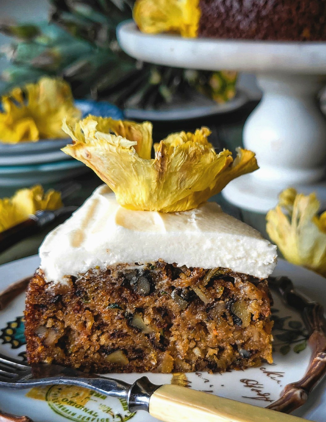 Slice of zucchini carrot cake with cream cheese icing and pineapple flower topper