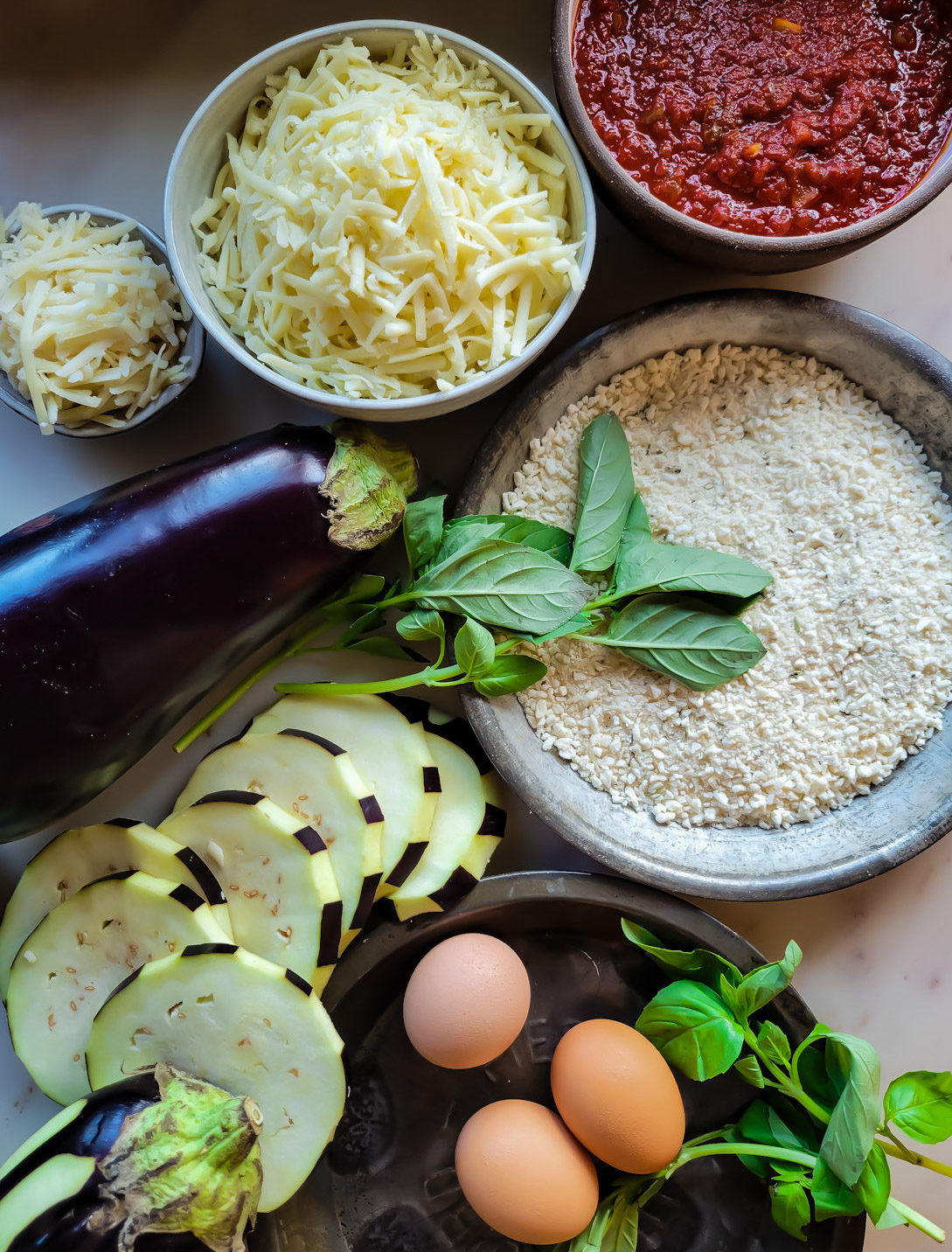 Ingredients for Lighter Eggplant Parmesan, eggplant, marinara sauce, cheeses, almond and panko dredge, basil, and eggs