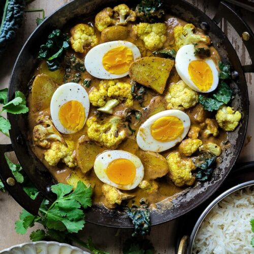 Egg, Potato and Cauliflower Curry in a skillet. Kale, and basmati rice are on the side.