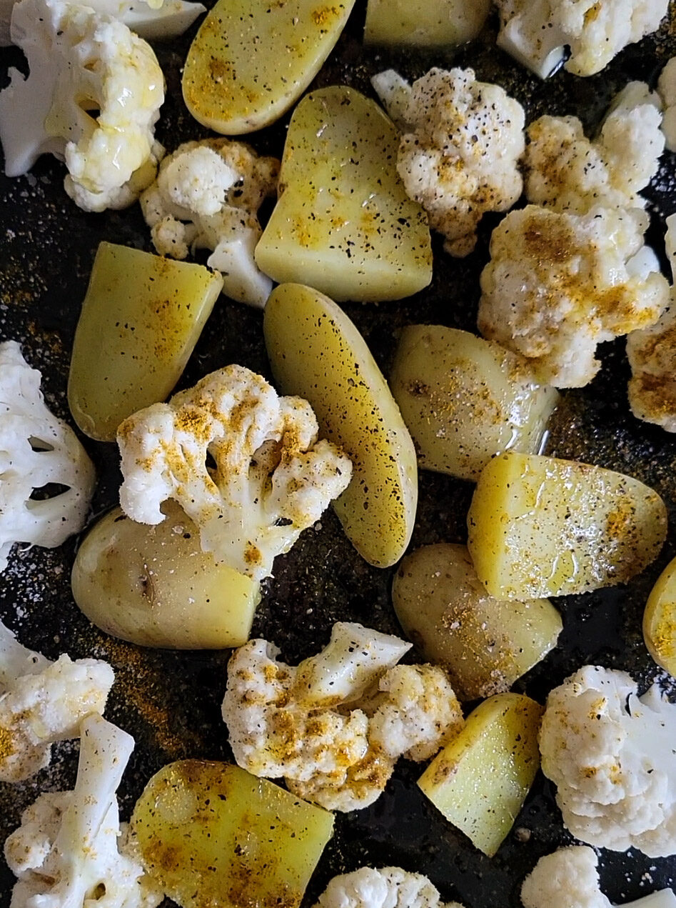close up of roasting potatoes and cauliflower for Egg Potato and Cauliflower curry.