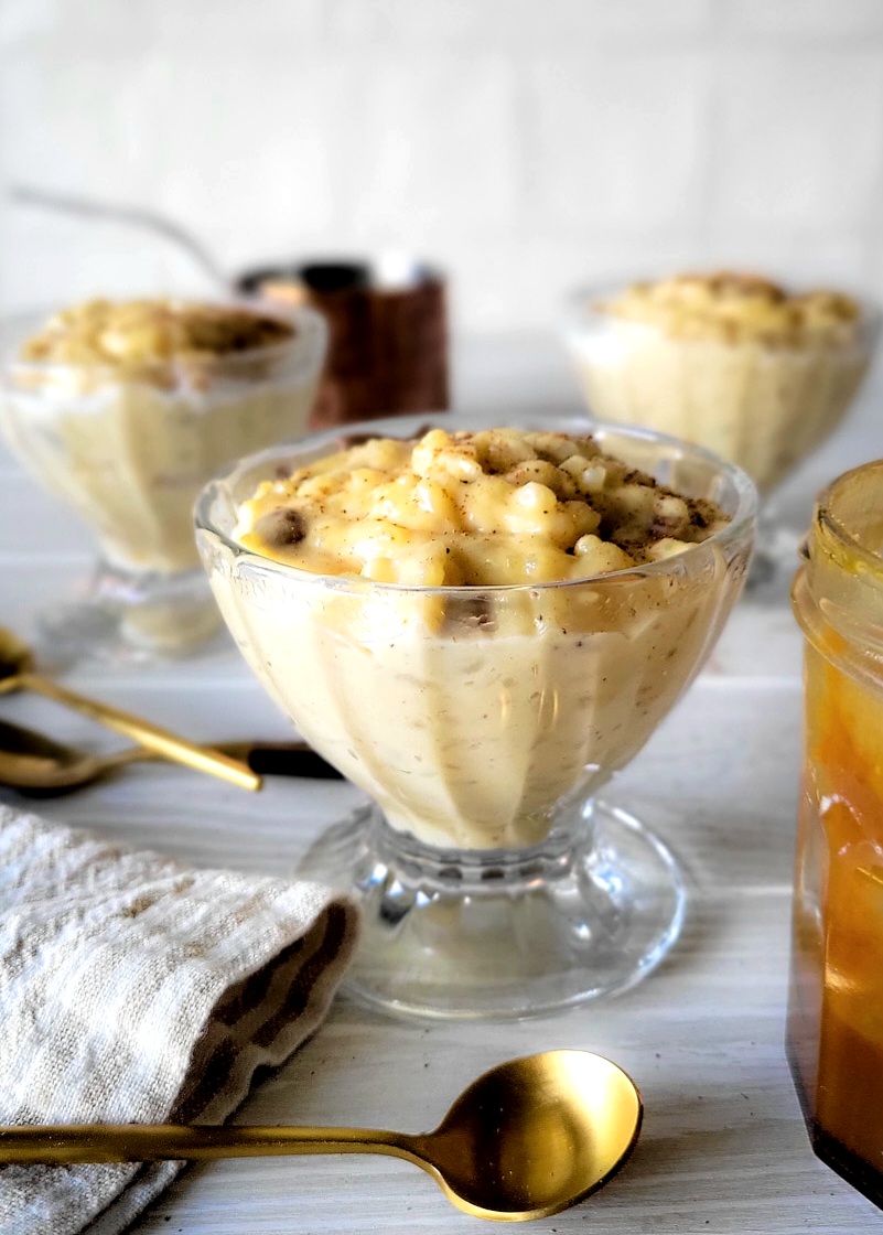 A bowl of rice pudding with cinnamon sprinkled on top, with a spoon at the side