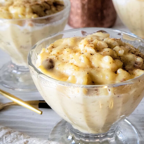 A bowl of rice pudding with cinnamon sprinkled on top, two more bowls in the background.