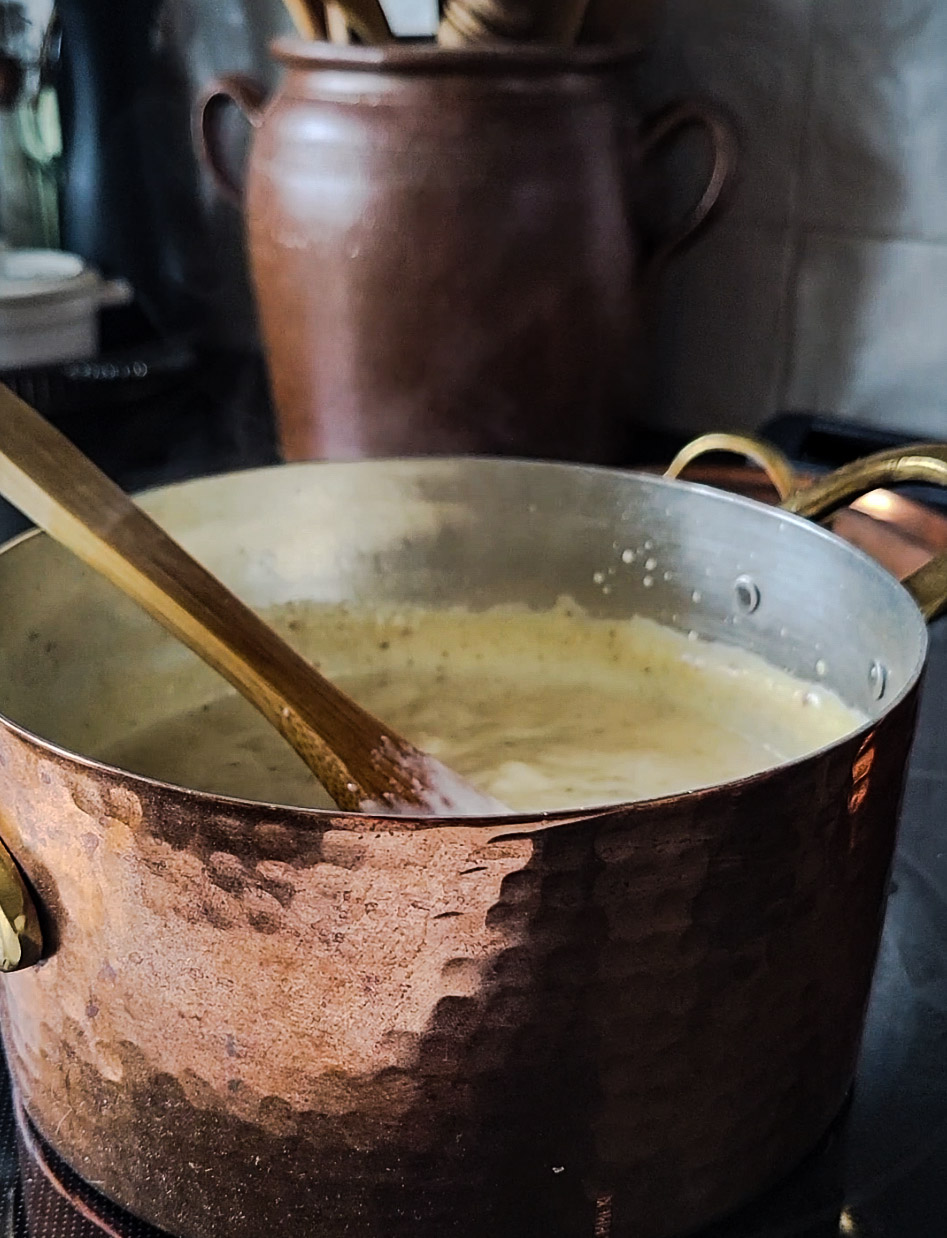 A copper pot on the stove, with rice pudding bubbling in it.