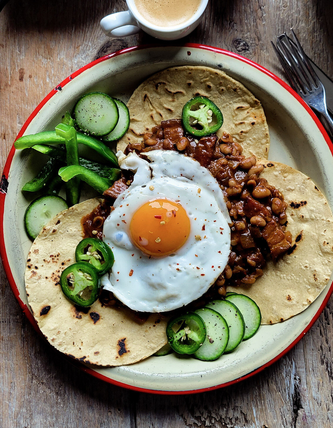A plate with tortillas, baked beans and a fried egg are ready to eat for breakfast.