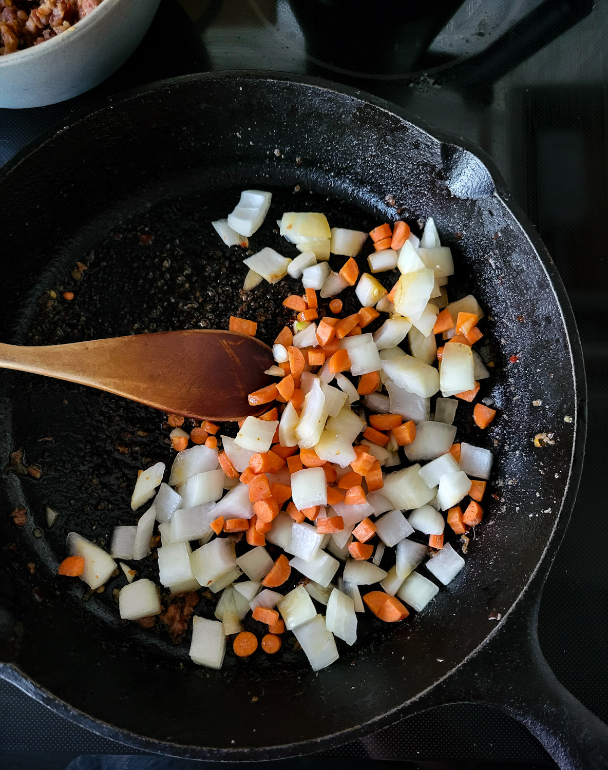 A skillet with onions and carrots about to be sautéed for Brothy Beans with Sausage and Kale