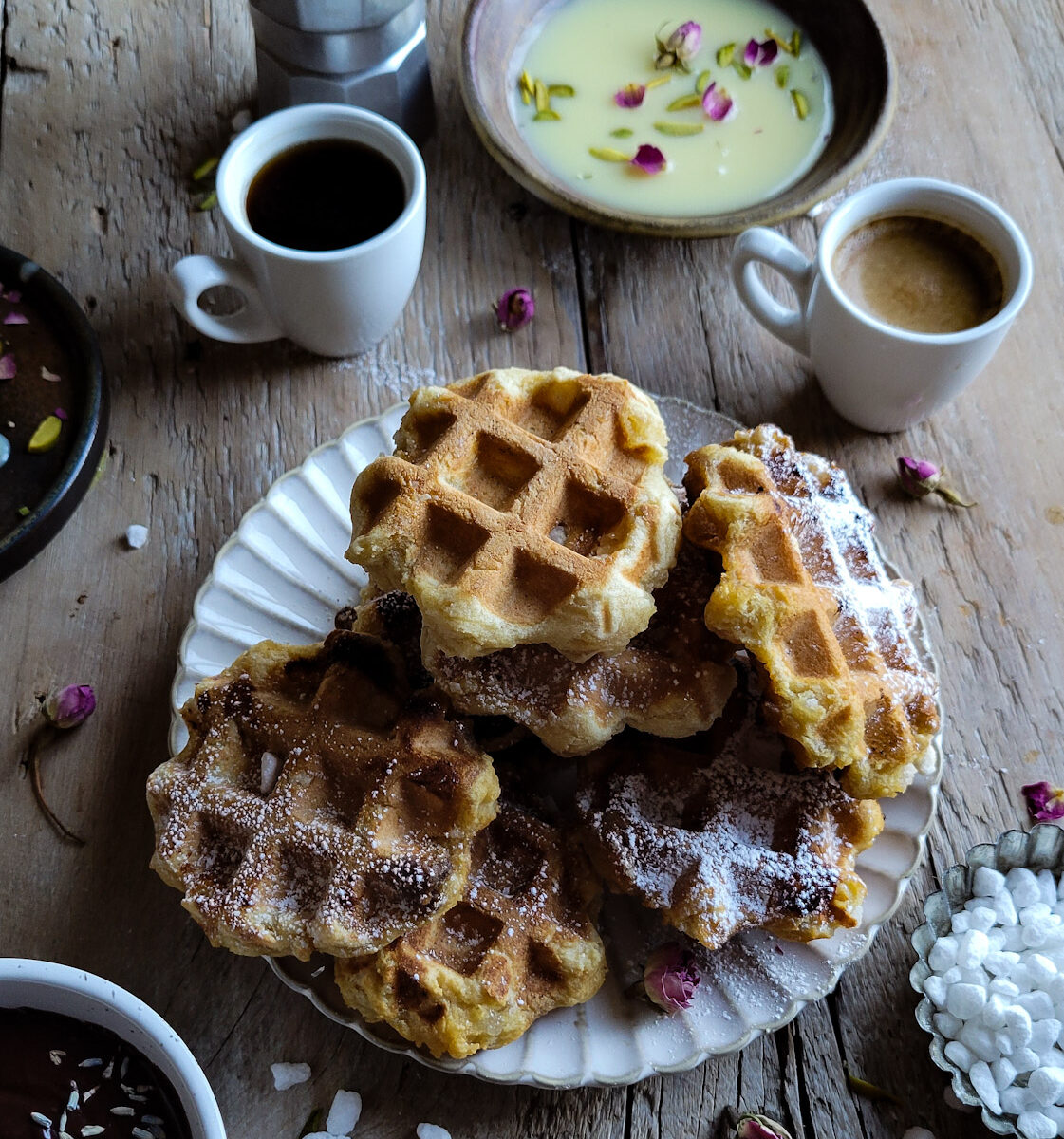 A plate piled high with Liege inspired Mochi Waffles with white chocolate dipping sauce and espresso in the background.