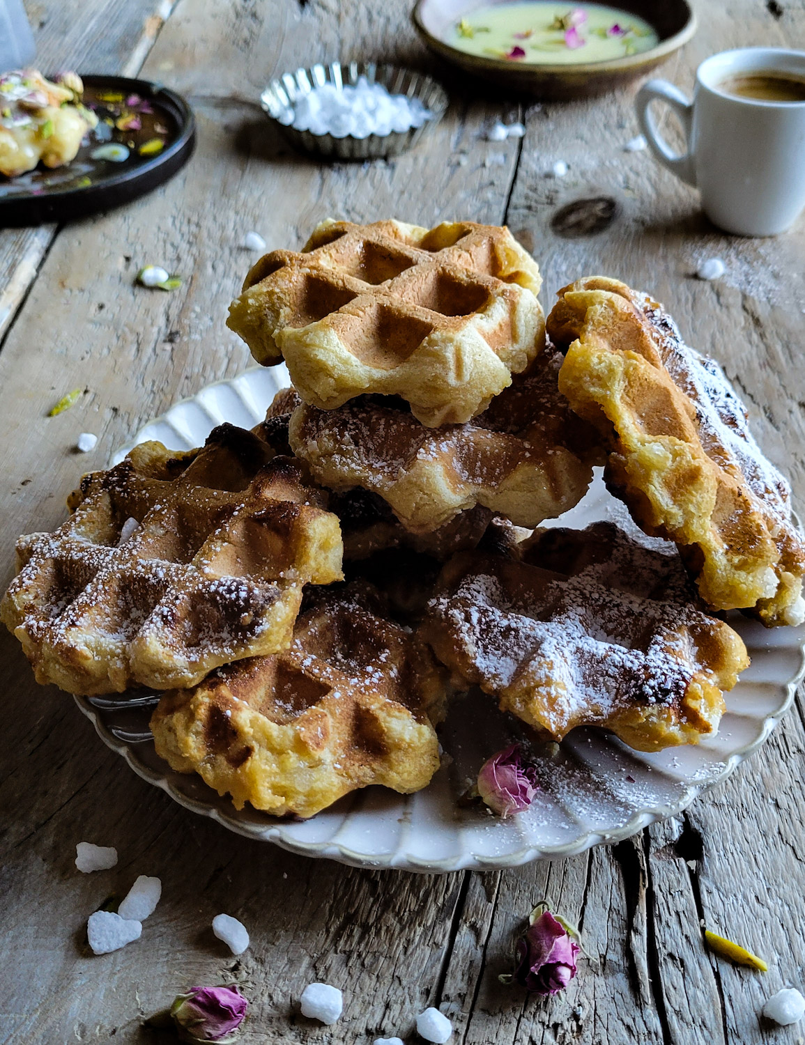 A plate piled high with Liege inspired Mochi Waffles with white chocolate dipping sauce and espresso in the background.