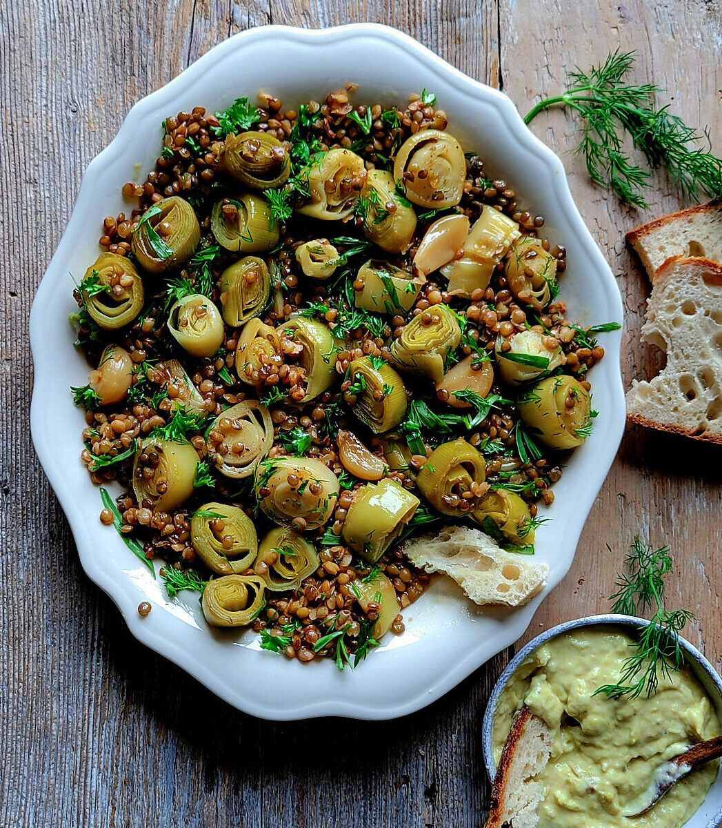 A serving plate filled with Leek Confit and Lentils, Leek Cream to the side with crusty bread.