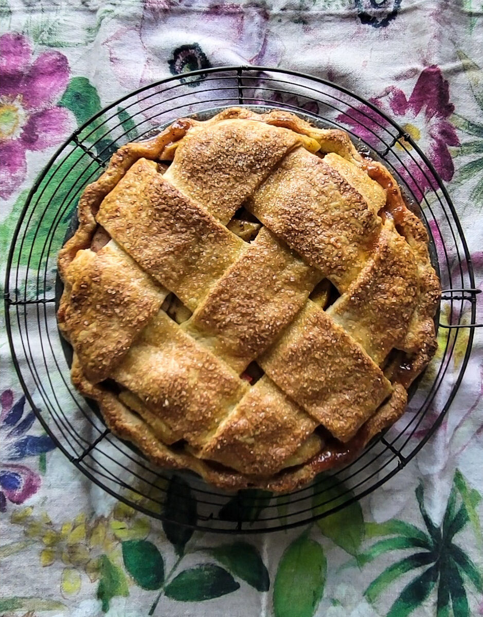 Fully baked Apple Rhubarb Pie on a cooling rack.