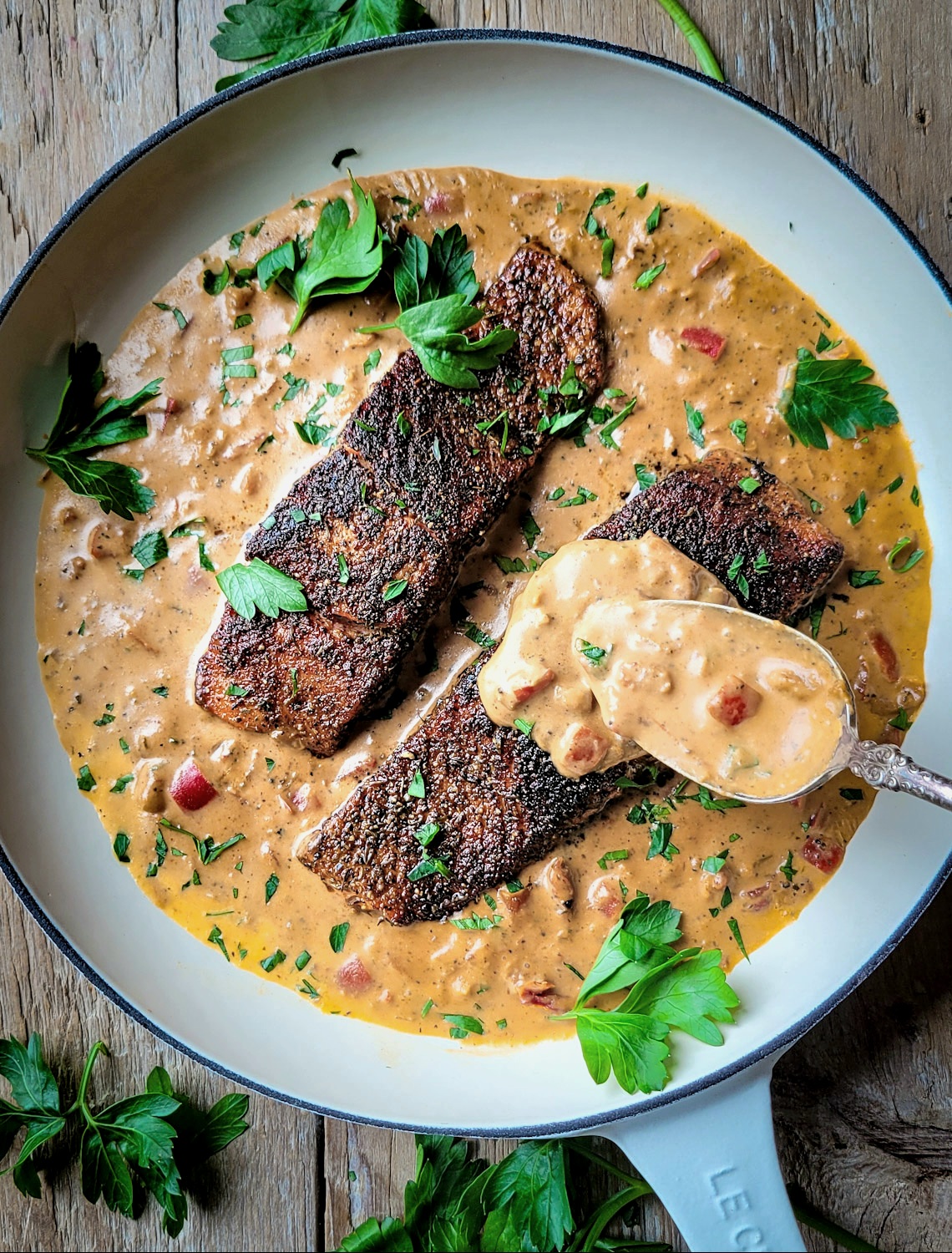 A skillet filled with Creole Cream Sauce and Air Fryer Salmon.