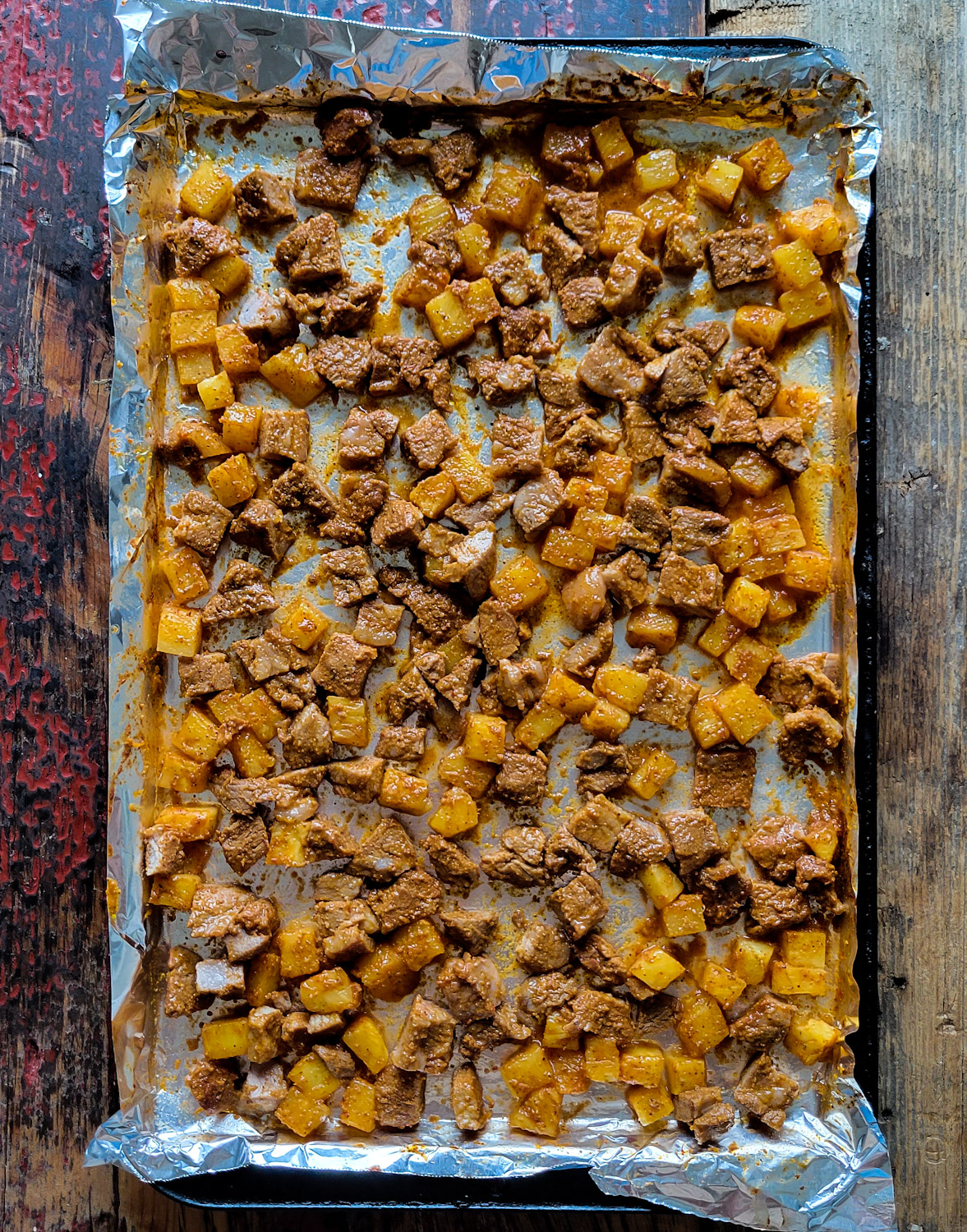 Al Pastor Marinated Pork and Pineapple cubed and spread out on a Baking sheet.