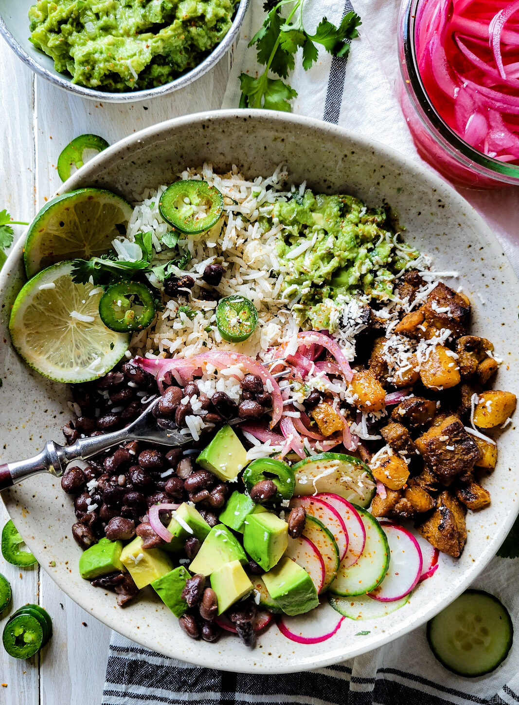 A finished bowl with all the ingredients for an Al Pastor Taco Bowl. Cilantro Rice, black beans, grilled pork and pineapple, guacamole and pickled onions round out the meal.