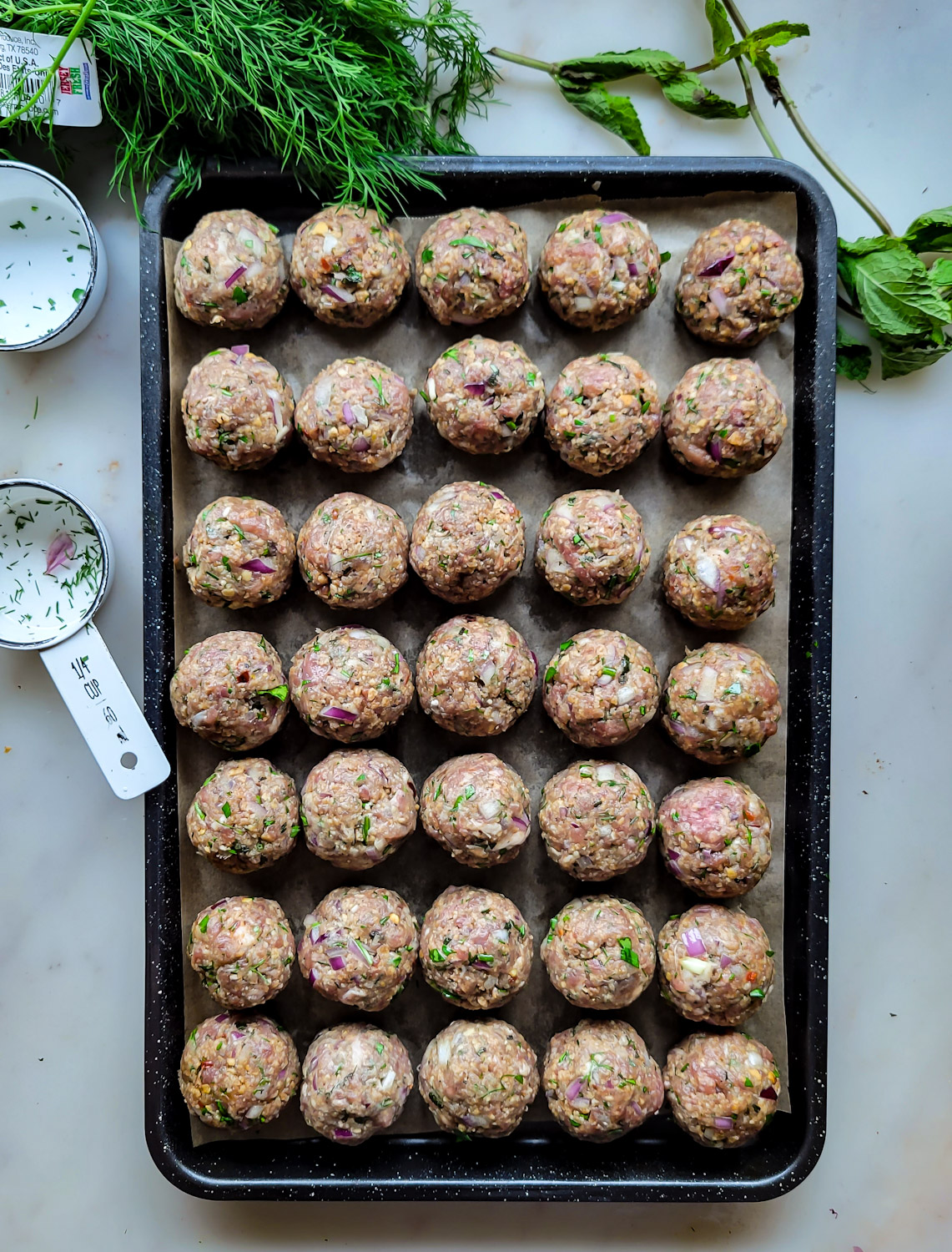 A baking sheet filled with Feta Stuffed Greek Meatballs ready to be frozen.