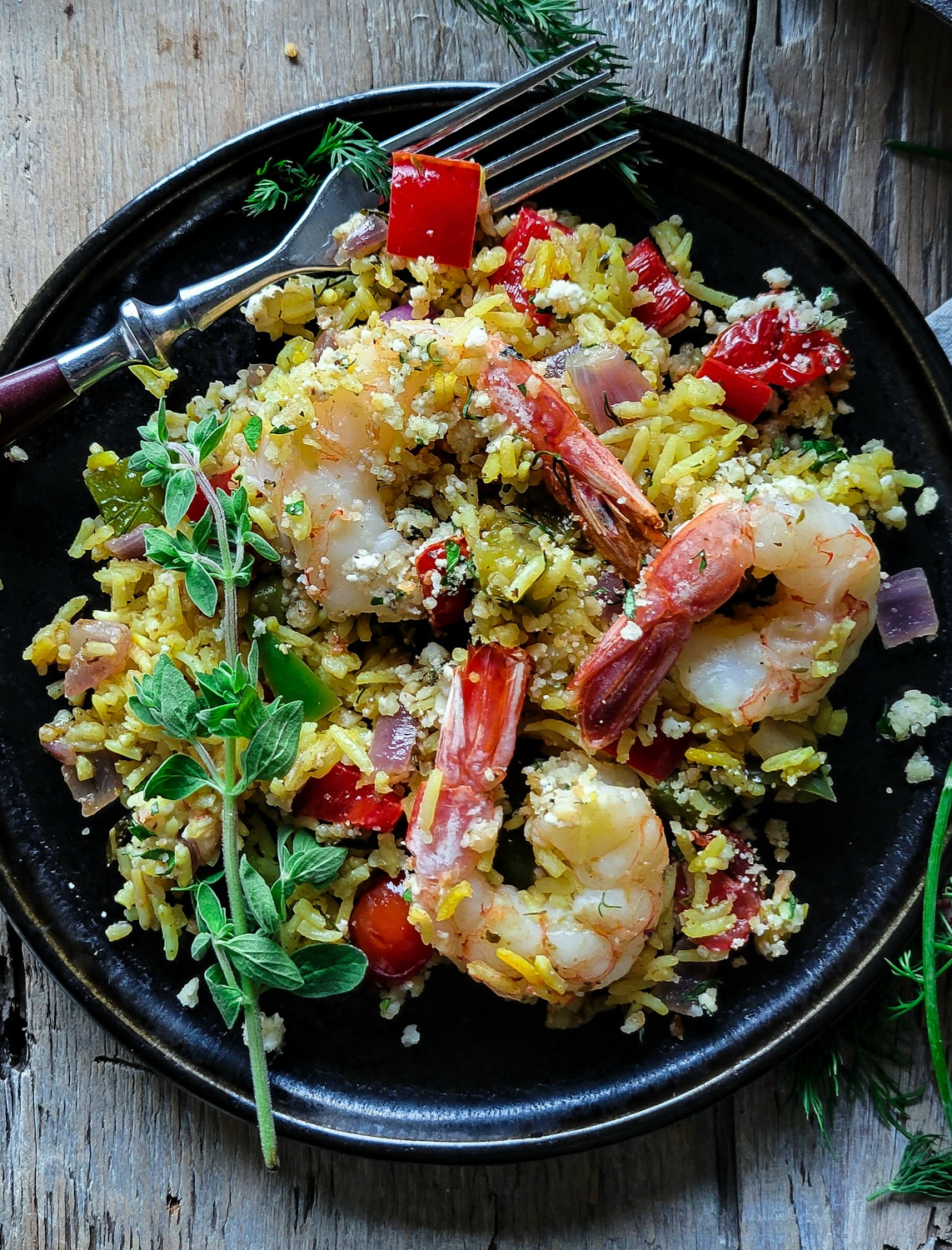 A plate is filled with Mediterranean Shrimp and Rice Bake, topped with fresh oregano.