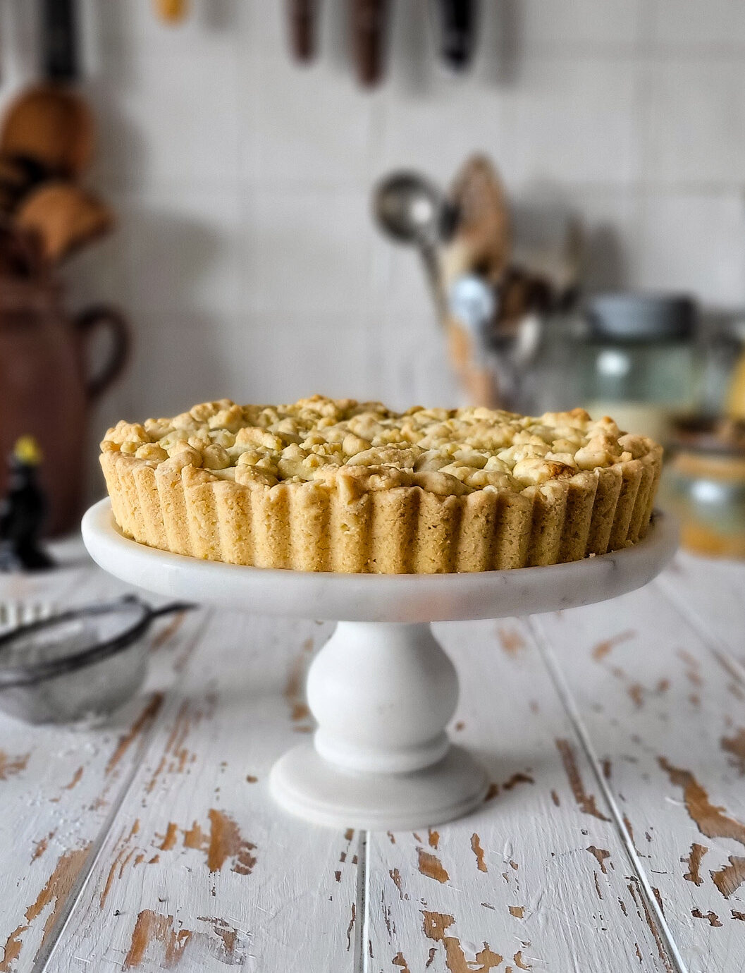 A freshly baked Salted Bourbon Caramel Apple Crostata sitting on a cake stand.