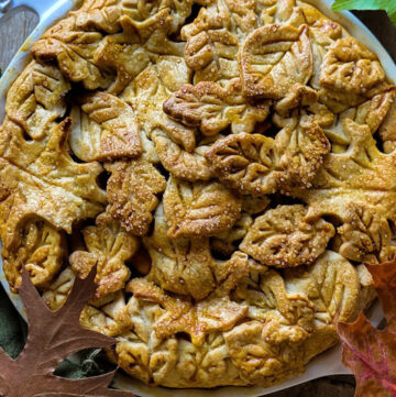 Close up of a Salted Bourbon Caramel Apple Pie. The pastry is created from many pastry leaves, covererd in egg wash and raw sugar.