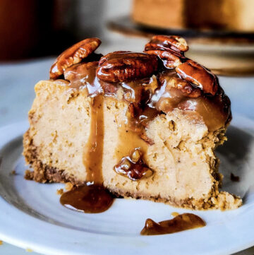 A slice of Pecan Praline Pumpkin Cheesecake with the caramel and nuts dripping down the sides.