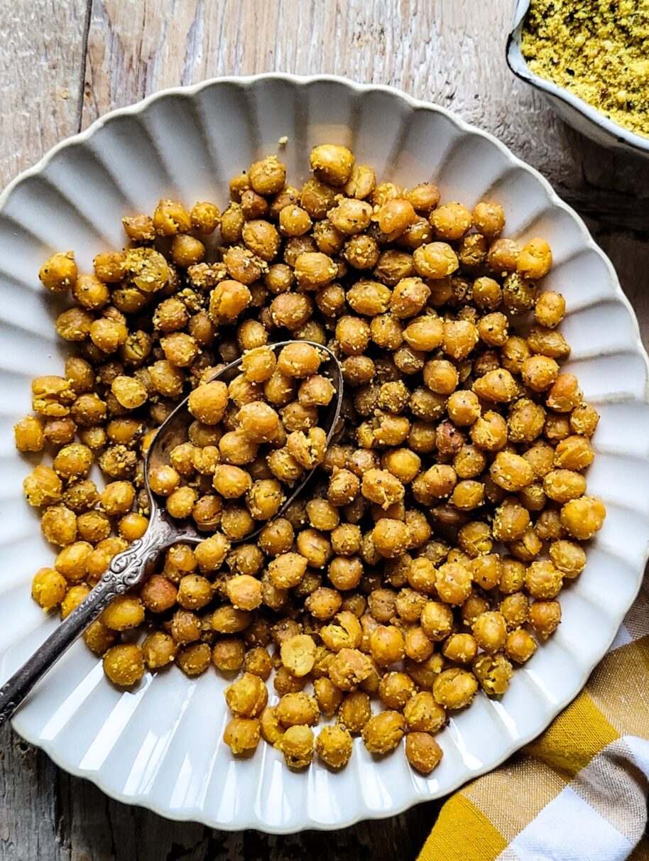 A bowl filled with Dukkah Roasted Chickpeas, with dukka spice blend to the side.