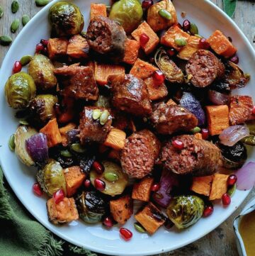A plate filled with Roasted Autumn Vegetables and Sausages with a Maple Vinaigrette.
