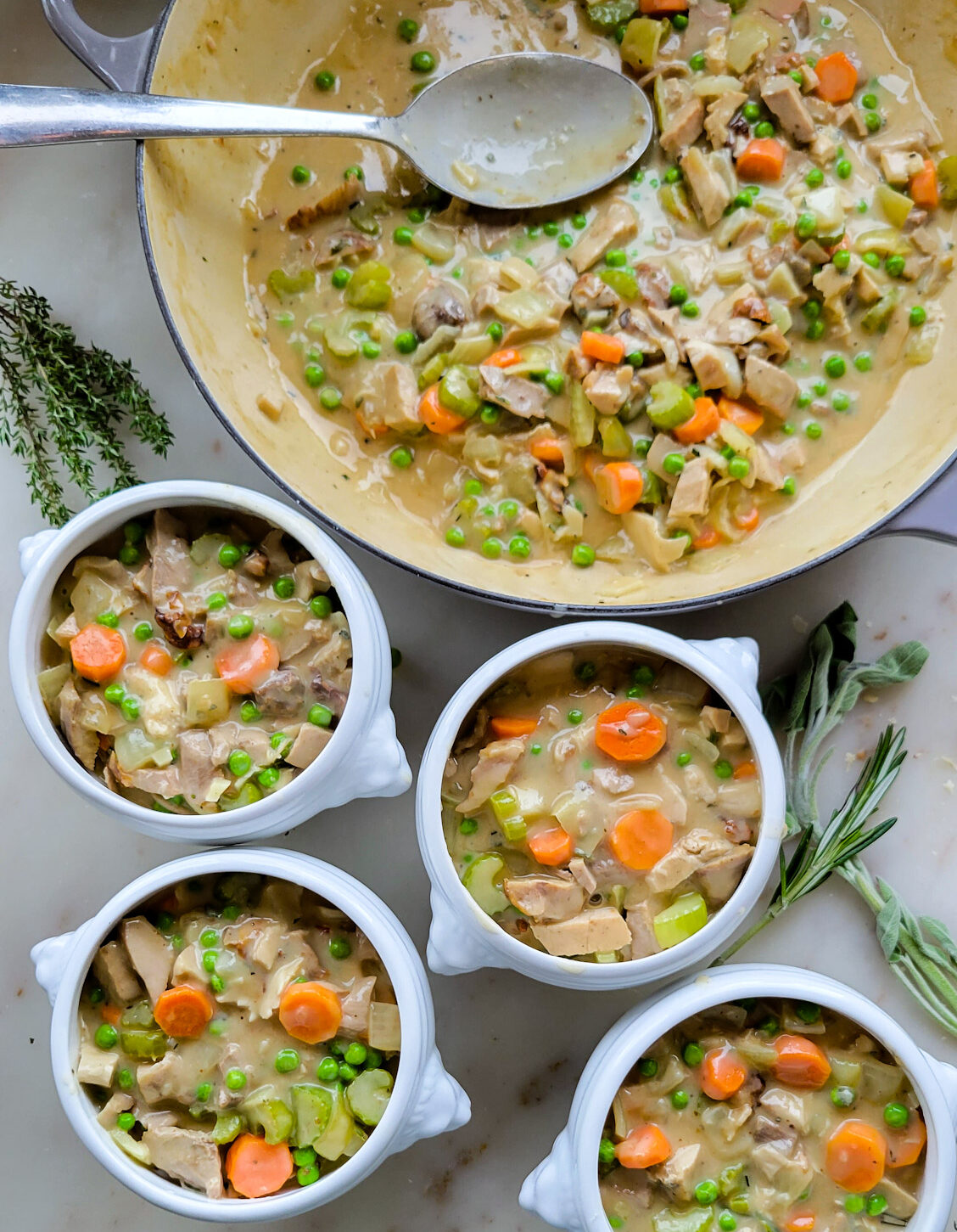 Filling the individual bowls with the Sage and Cider Turkey Pot Pie filling.