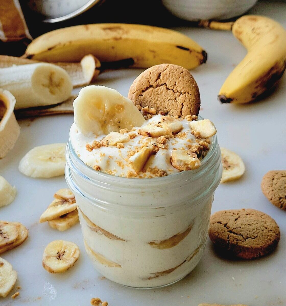 Classic Banana Pudding in a mason jar topped with a ginger snap cookie and banana chips.