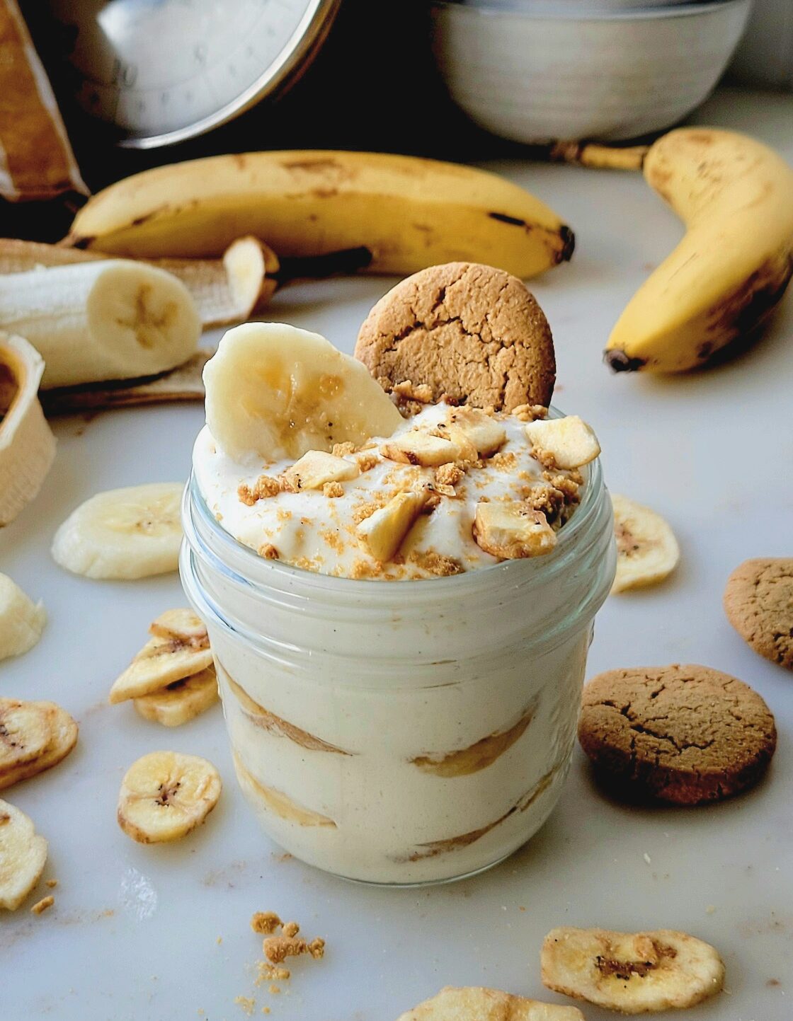 Classic Banana Pudding in a mason jar topped with a ginger snap cookie and banana chips.