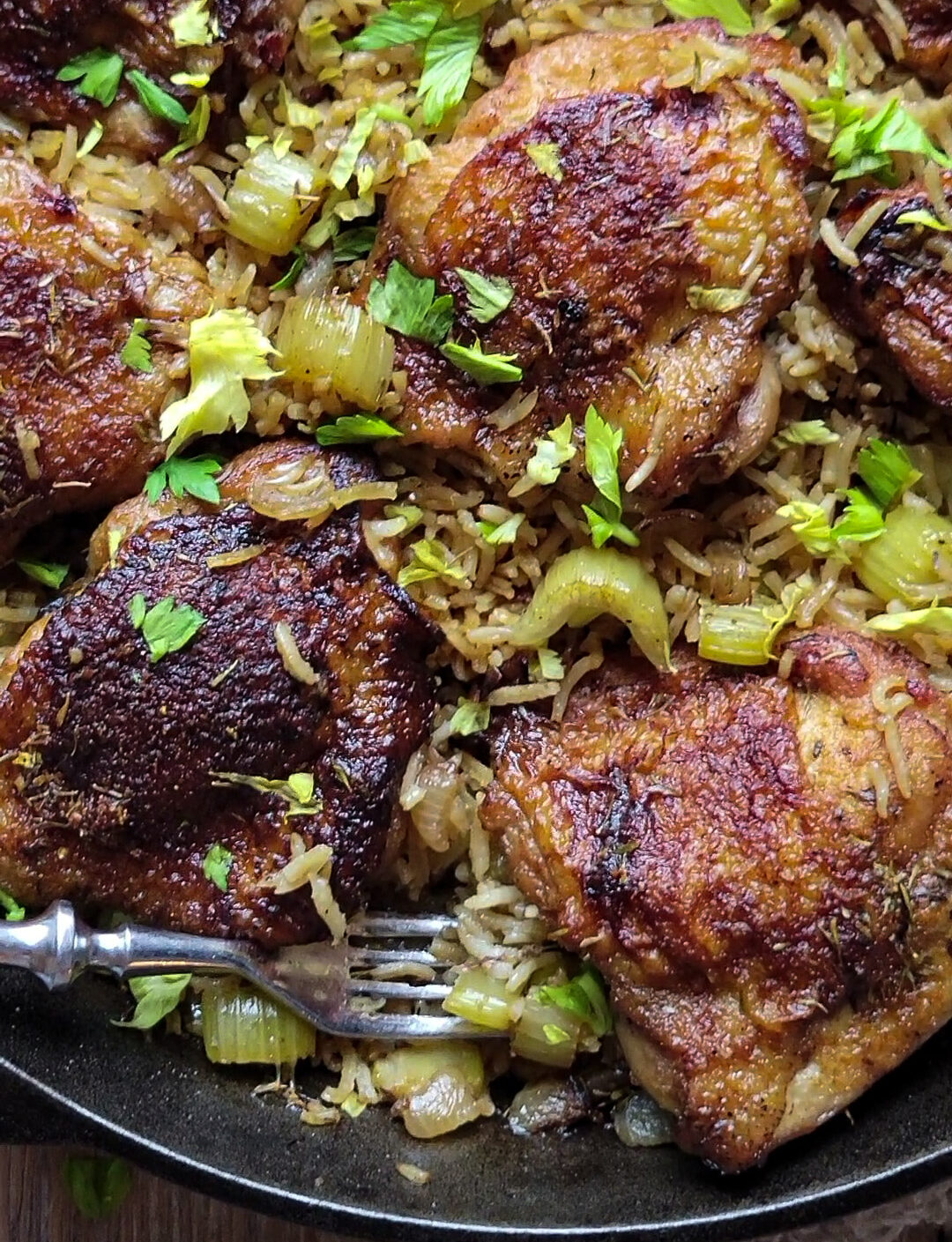 Close up of a skillet filled with Mama's Chicken and Rice, with a fork in the rice.