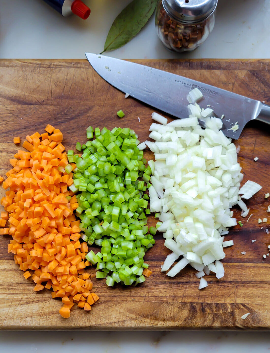 A cutting board with the finely diced vegetables used as the flavour base for Tuscan Braised Beans and Kale