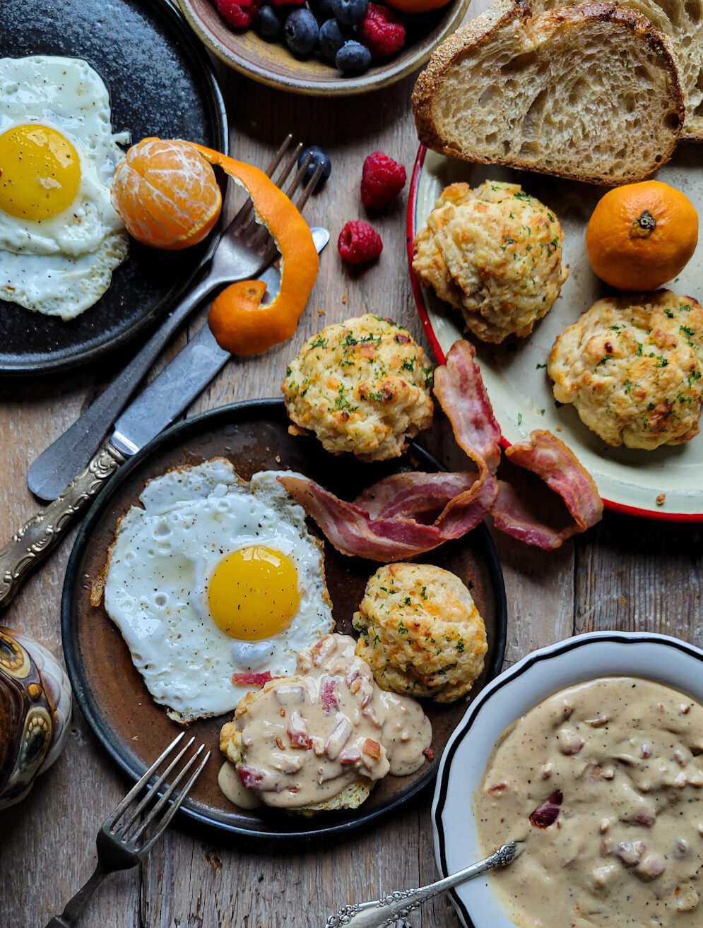 A breakfast plate filled with a sunny side up egg, bacon and an Easy Cheddar Drop Biscuit smothered in Bacon Gravy.