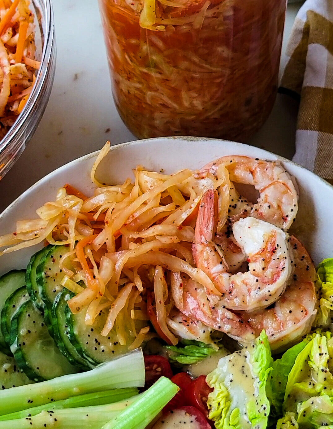 A shrimp bowl with kimchi sauerkraut, with a jar of Kimchi Sauerkraut in the background.