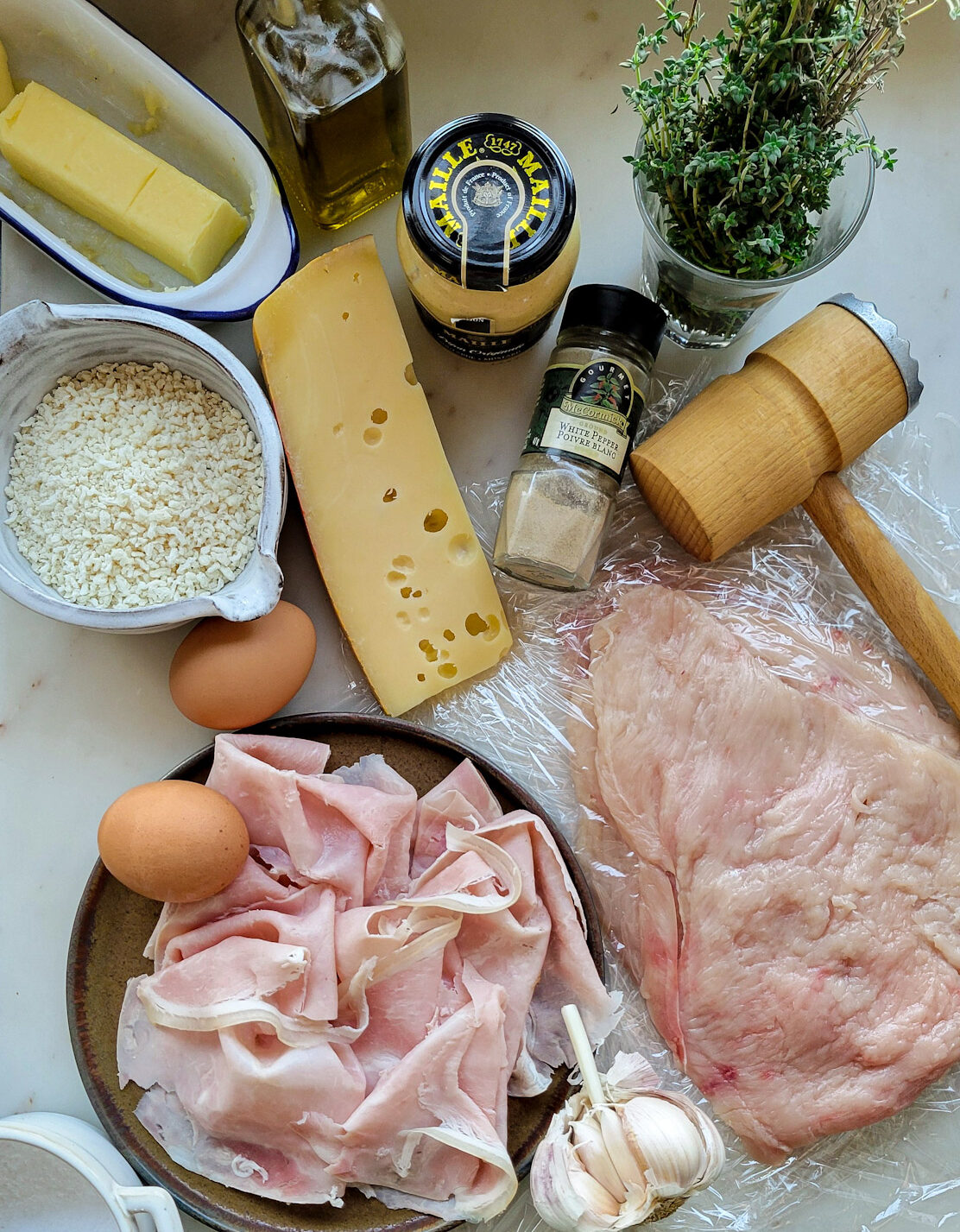 Ingredients needed to make Chicken Cordon Bleu are set out on the counter/