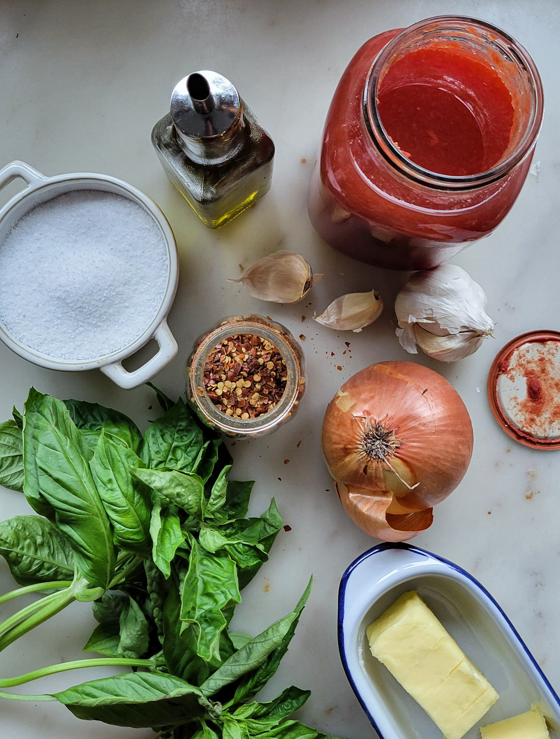 Ingredients needed to make Basil and Garlic Infused Tomato Sauce are set out on the counter.