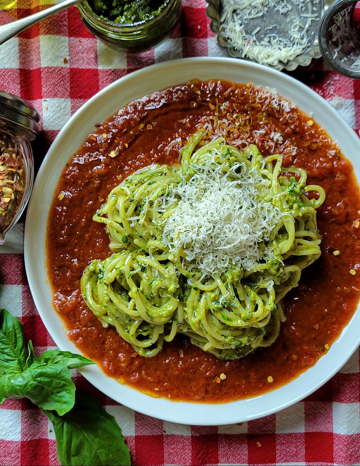 A plate filled with Pesto Cream Pasta sitting on a bed of Basil and Garlic Infused Tomato Sauce