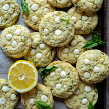 A baking sheet is filled with Lemon Basil Cookies with White Chocolate and Pistachios.