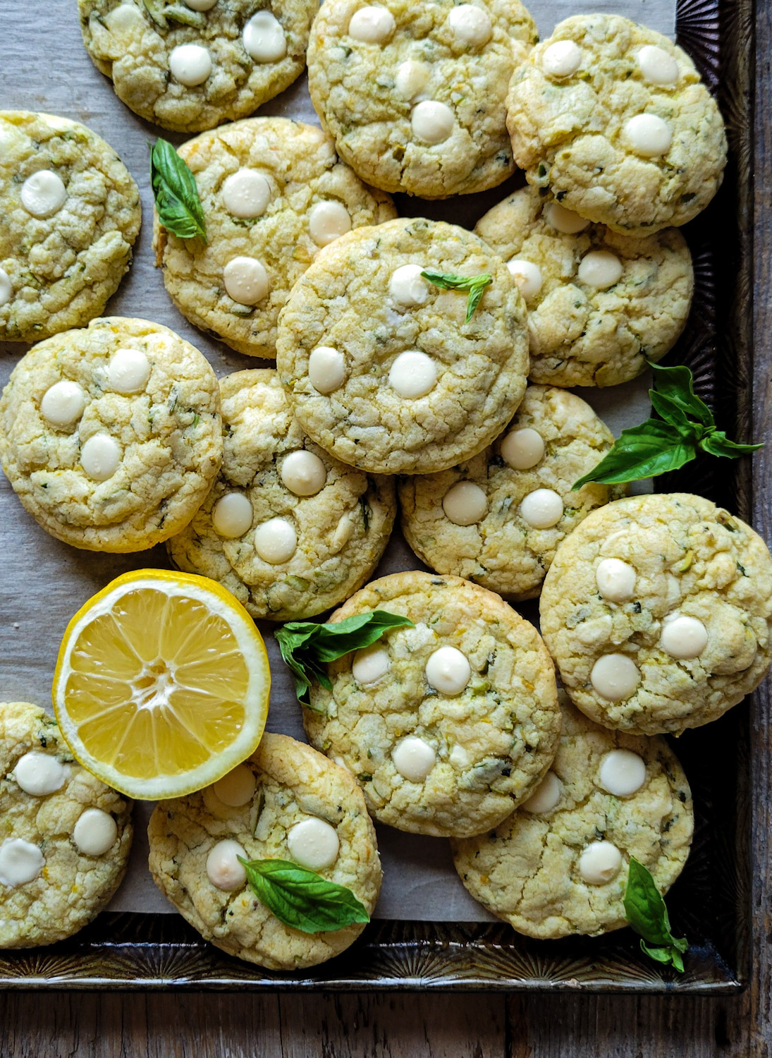 A baking sheet is filled with Lemon Basil Cookies with White Chocolate and Pistachios.