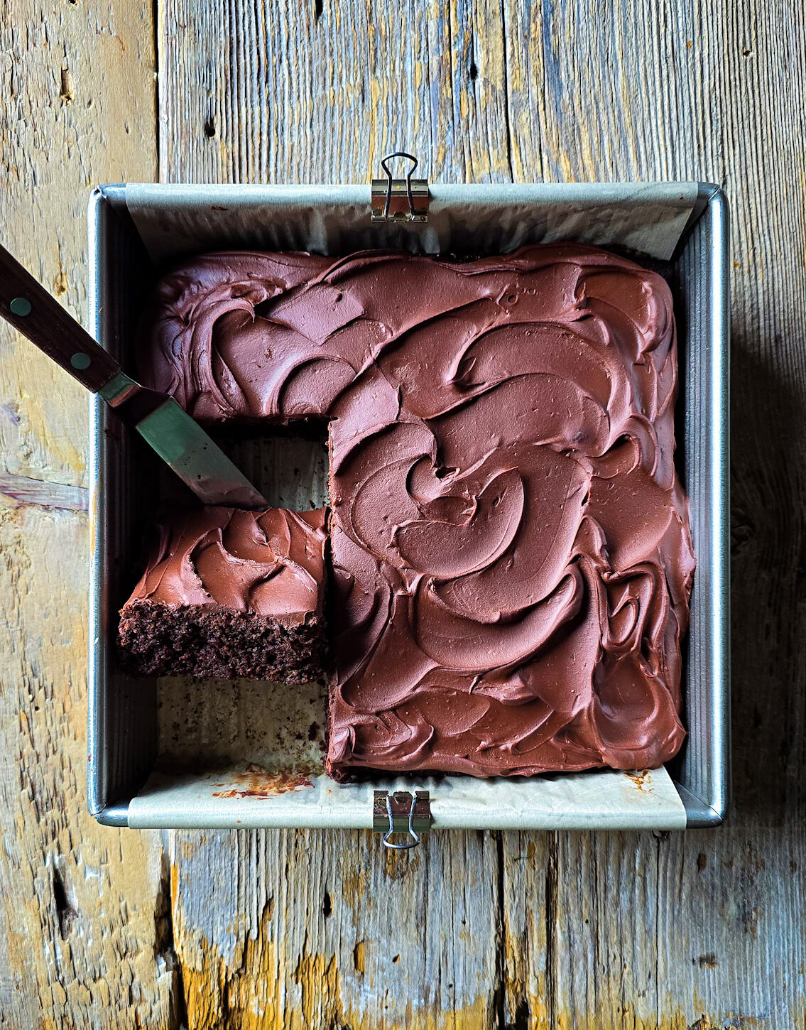 Looking down on a Double Chocolate Zucchini Cake with one slice lifted up to see the luscious interior.