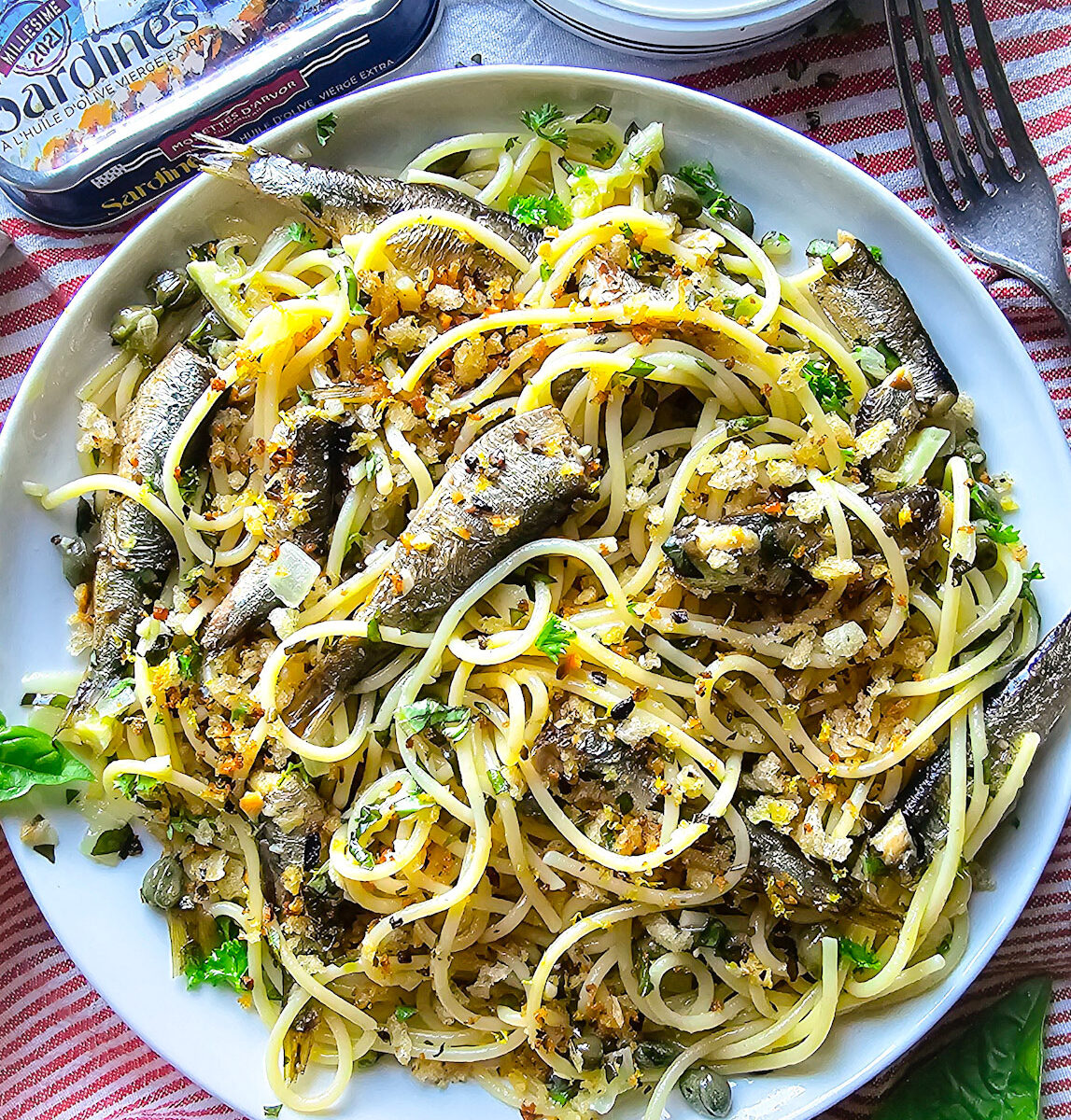 Close up of a plate of Sardine and Lemon Pangrattato Pasta, with a tin of sardines to the side.