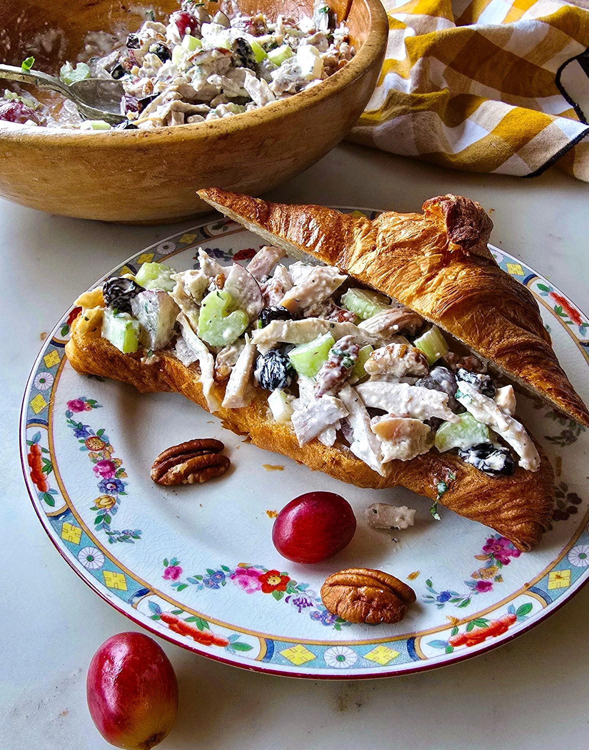 A sliced croissant is filled with Leftover Turkey Diner Salad, with more salad in a bowl to the back.