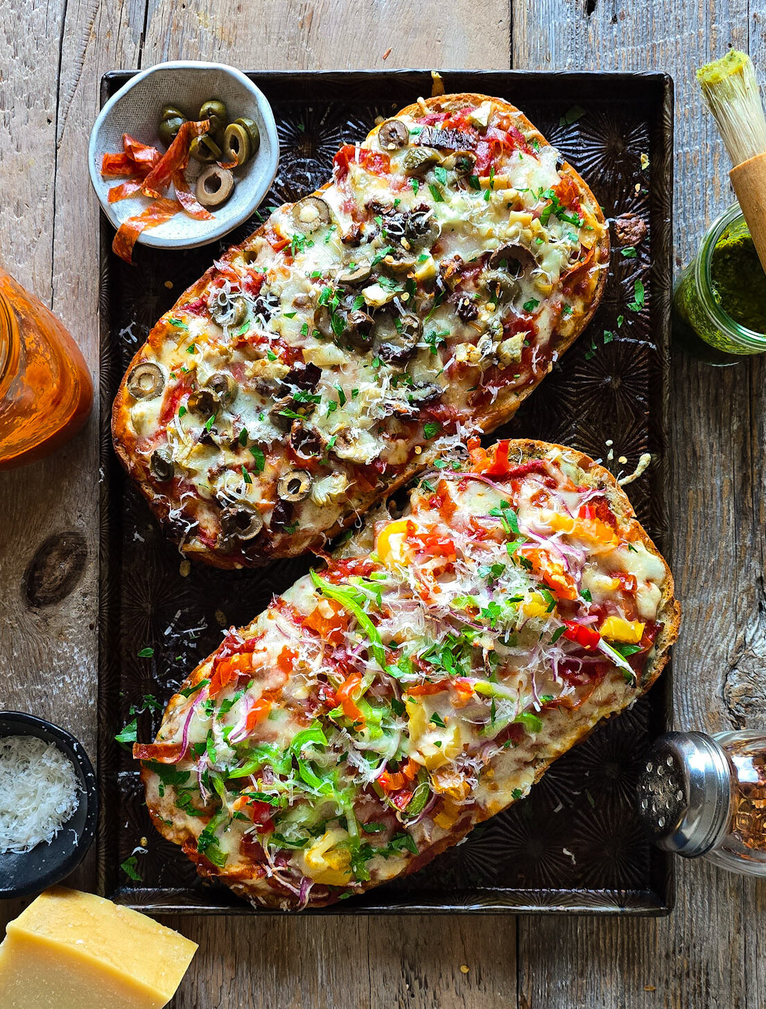 Fresh out of the oven, two halves of French Bread Pizza sit on a baking sheet ready to be sliced.