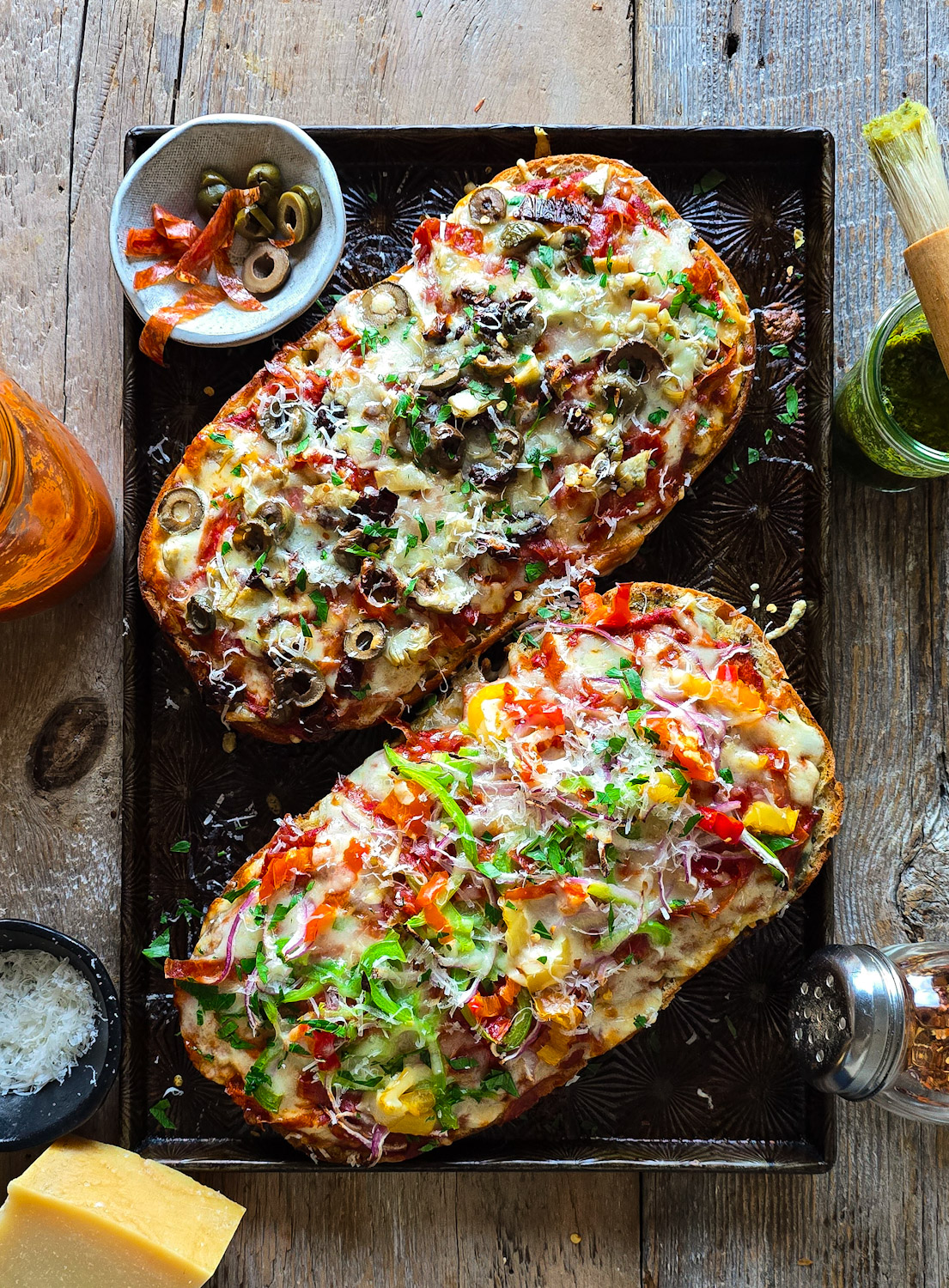 Fresh out of the oven, two halves of French Bread Pizza sit on a baking sheet ready to be sliced.