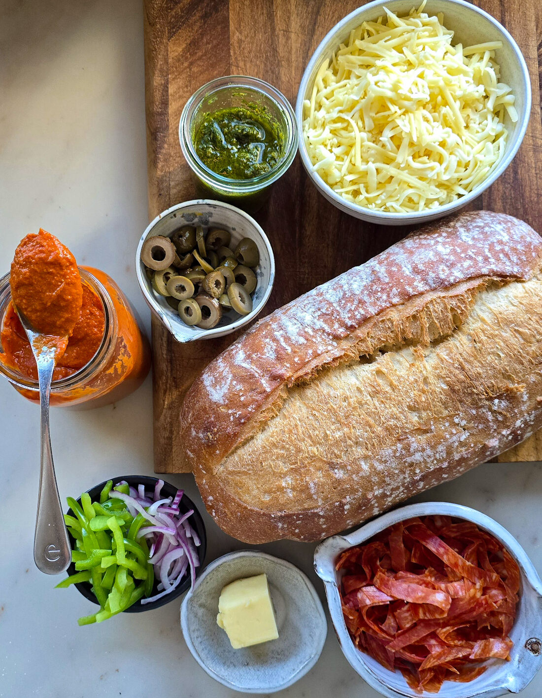 Ingredients needed to make French Bread Pizza are spread out on the counter.