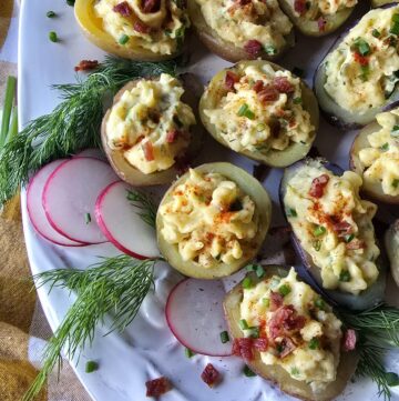 Close up of Devilled Mini Potatoes on a platter with dill fronds and radish slices