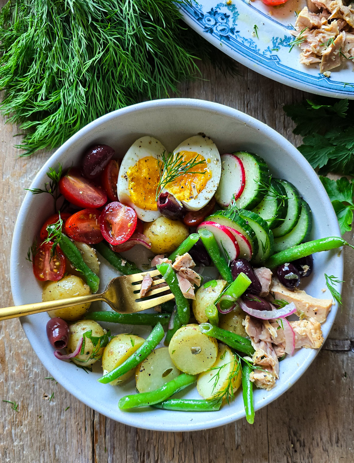 A individual bowl is filled with all the fixings for a Nicoise Salad Bowl.
