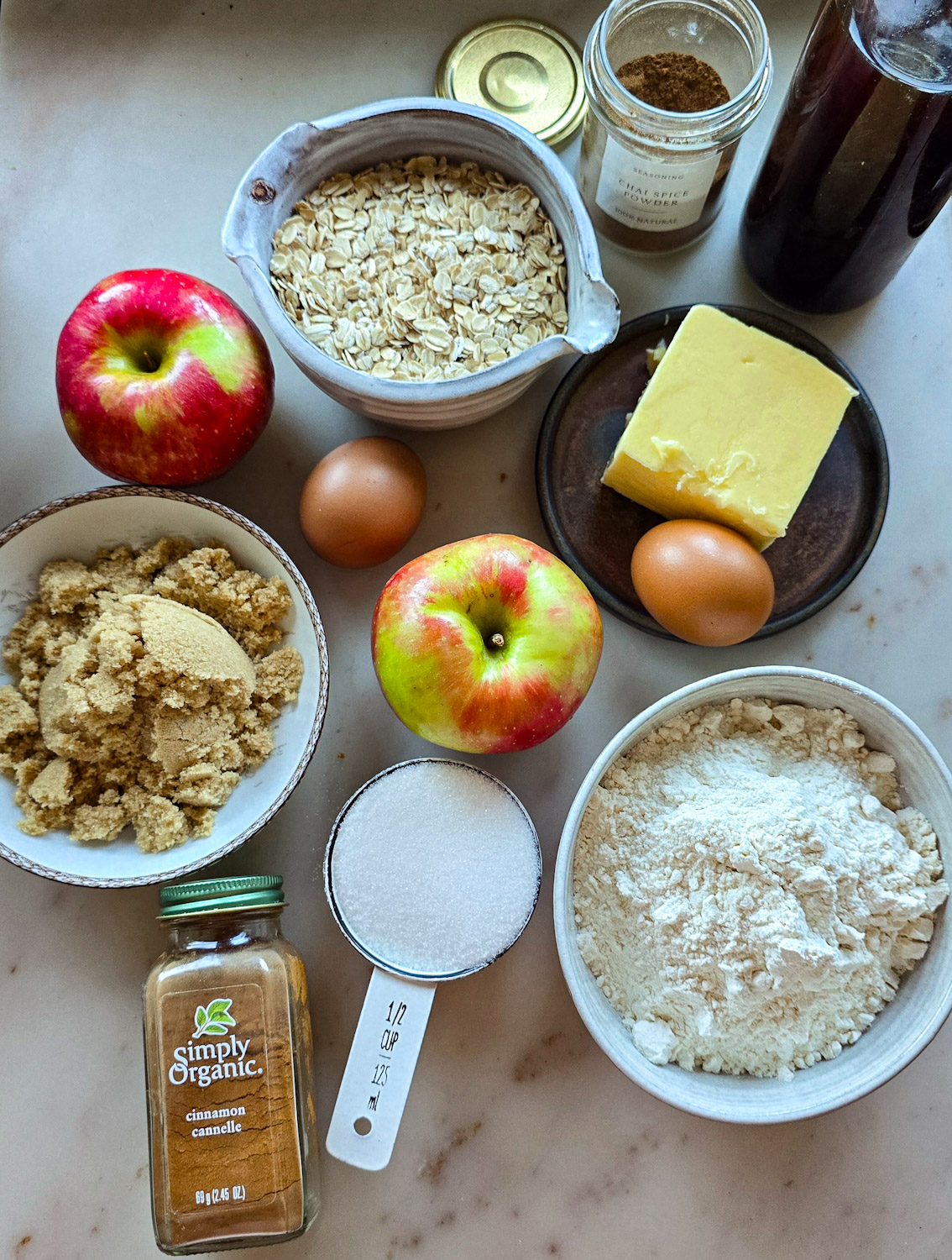 Ingredients needed to make Chewy Chai Apple Oatmeal Cookies are spread out on the counter.