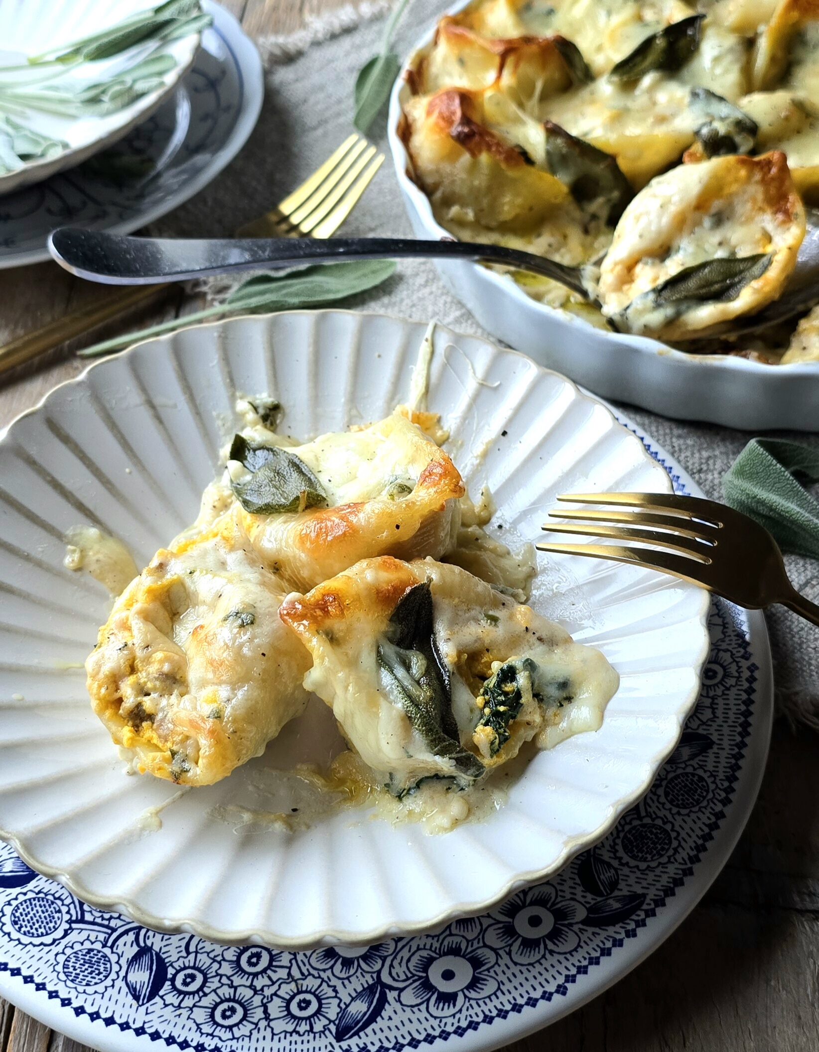 A portion of Squash, Kale and Sausage Stuffed Shells in on the plate, with the baking dish of more shells in the background.