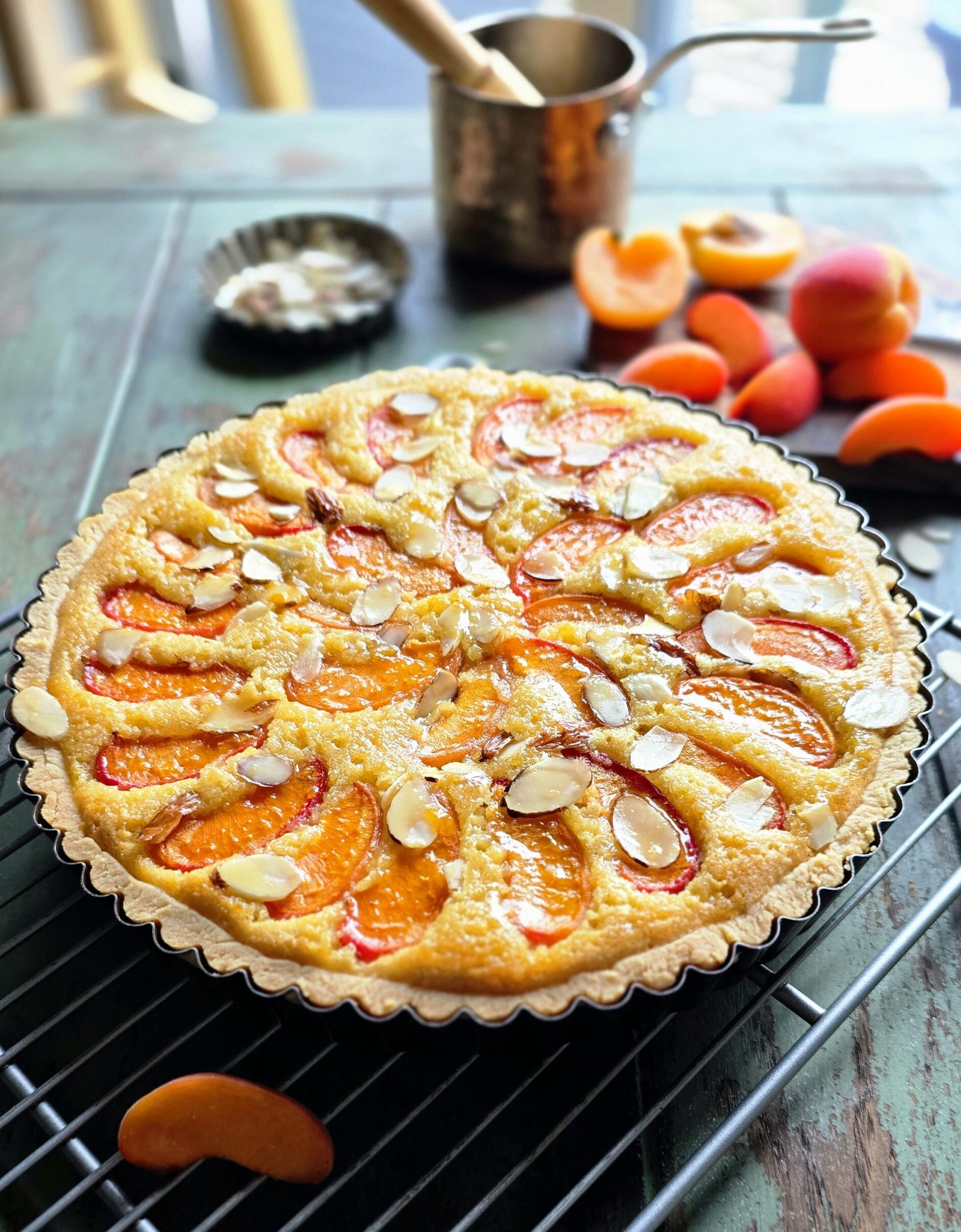 A freshly baked Apricot Frangipane Tart sits on the table ready to be brushed with warmed through apricot jam glaze.